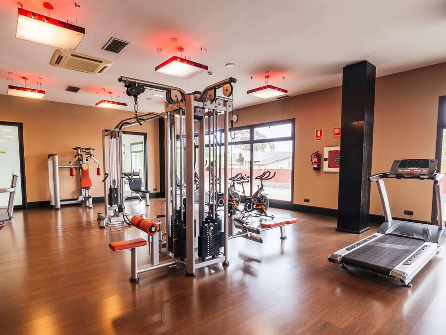Un gimnasio con diferentes equipos de ejercicio, como cintas de correr, bicicletas estáticas y máquinas de pesas.