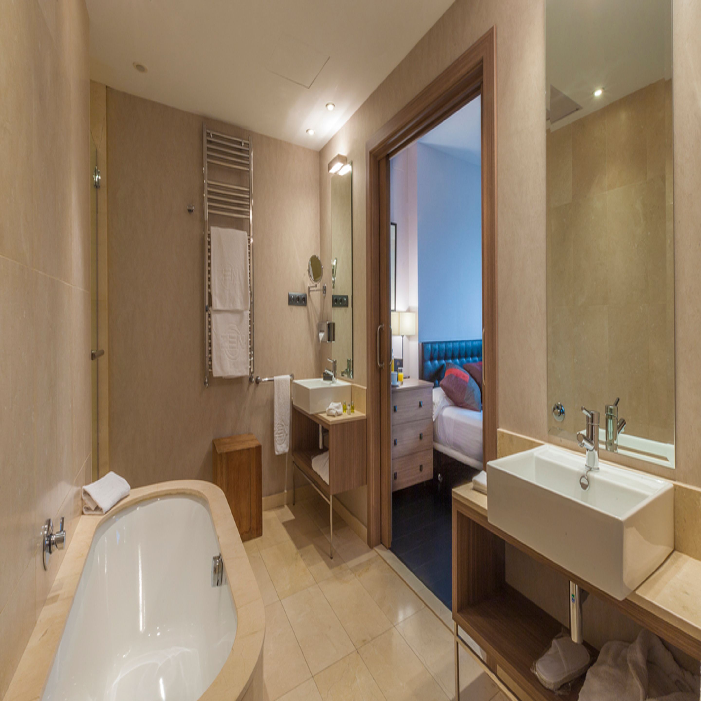 Un baño moderno con bañera, dos lavamanos y un espejo.