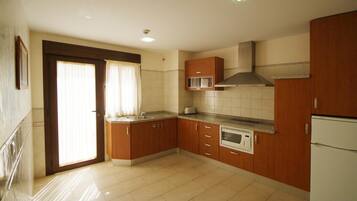 Una cocina con armarios de madera, microondas, estufa y refrigerador.
