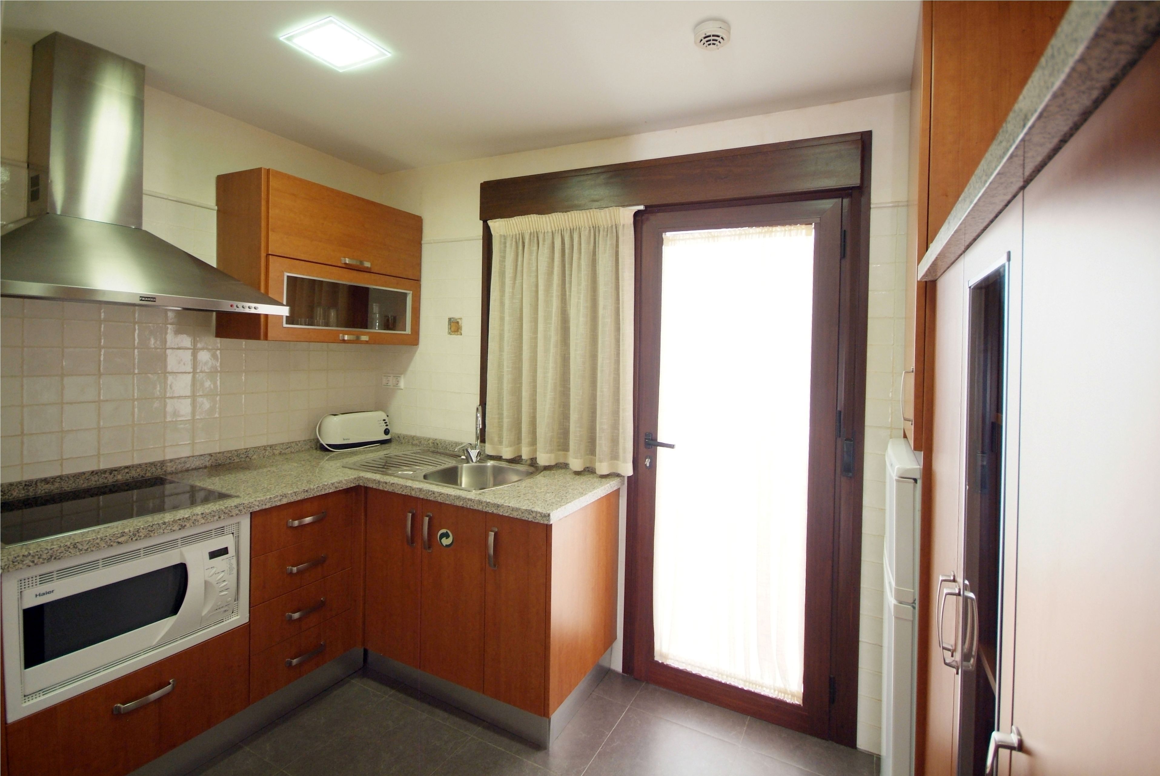 A kitchen with wooden cabinets, a stainless steel range hood, a microwave, and a toaster.