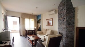Una sala de estar con chimenea de piedra, un sofá, una mesa de centro y un televisor.