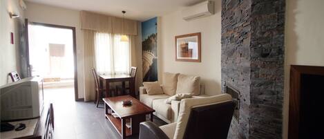 A living room with a stone fireplace, a sofa, a coffee table, and a television.