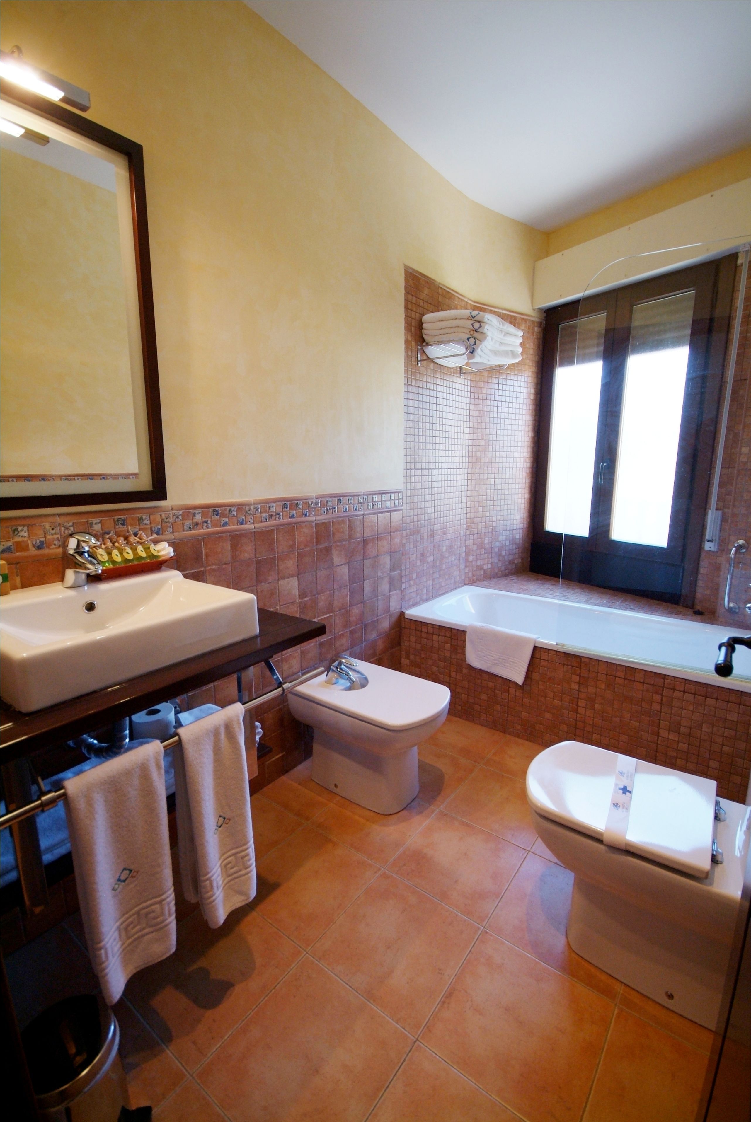 A bathroom with a sink, toilet, bidet, and bathtub.