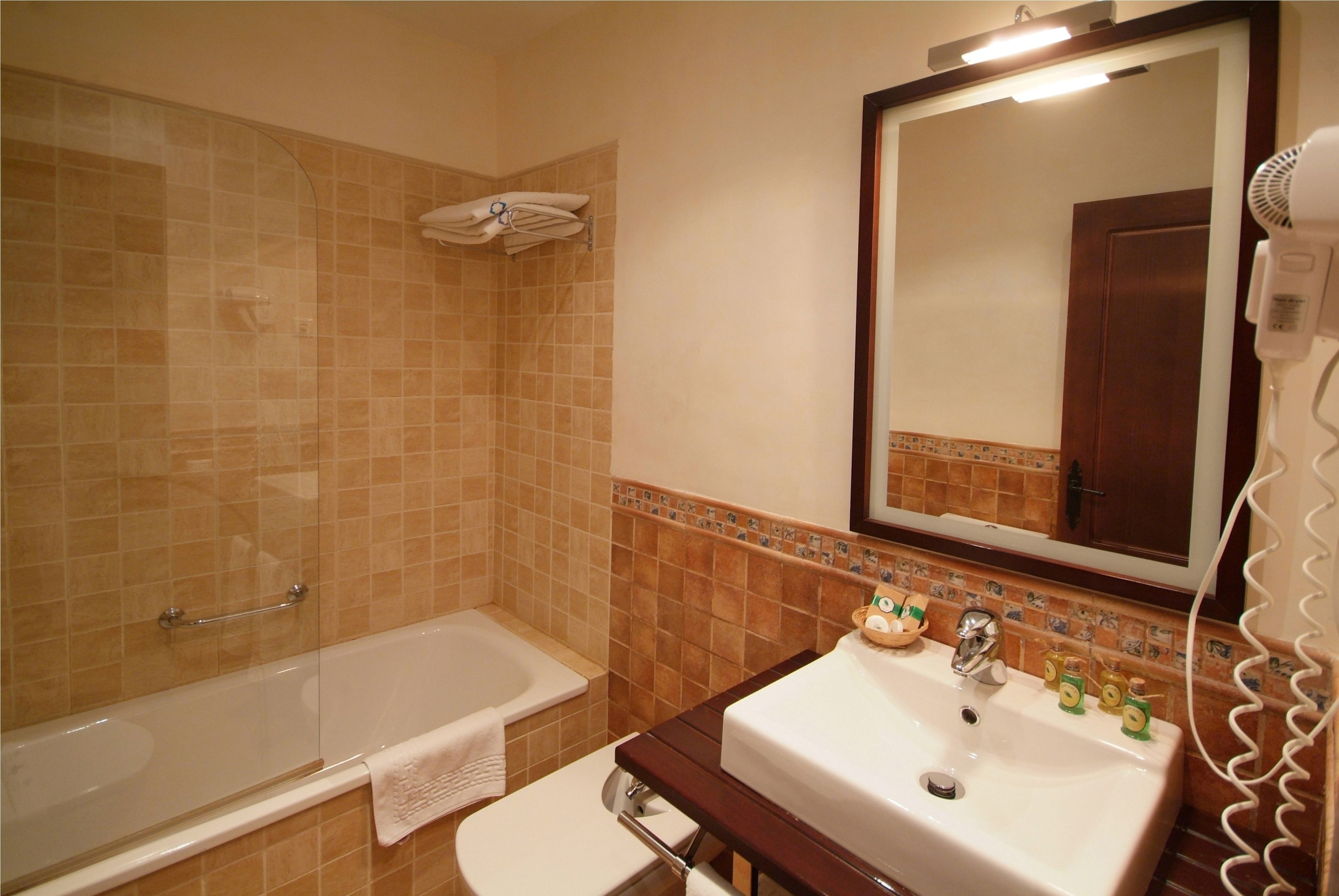 A bathroom with a bathtub, toilet, sink, and a hairdryer.