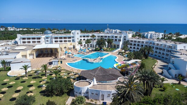 Et resort med en stor swimmingpool, flere loungeområder og havudsigt.