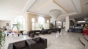 A spacious lobby with leather sofas, a billiards table, and large windows.