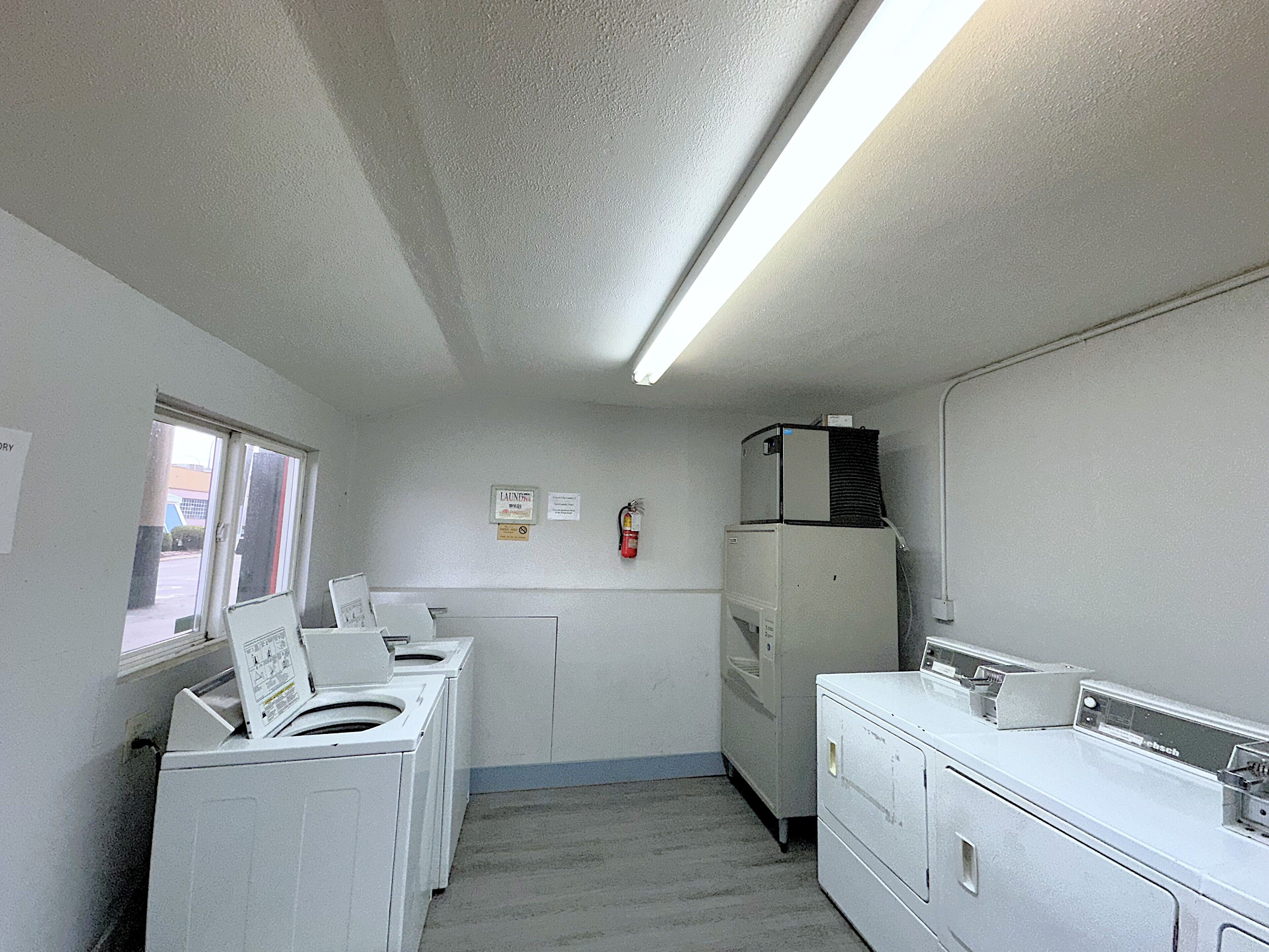 A laundry room with two washing machines, a dryer, and a refrigerator.