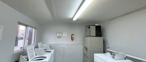 A laundry room with two washing machines, a dryer, and a refrigerator.