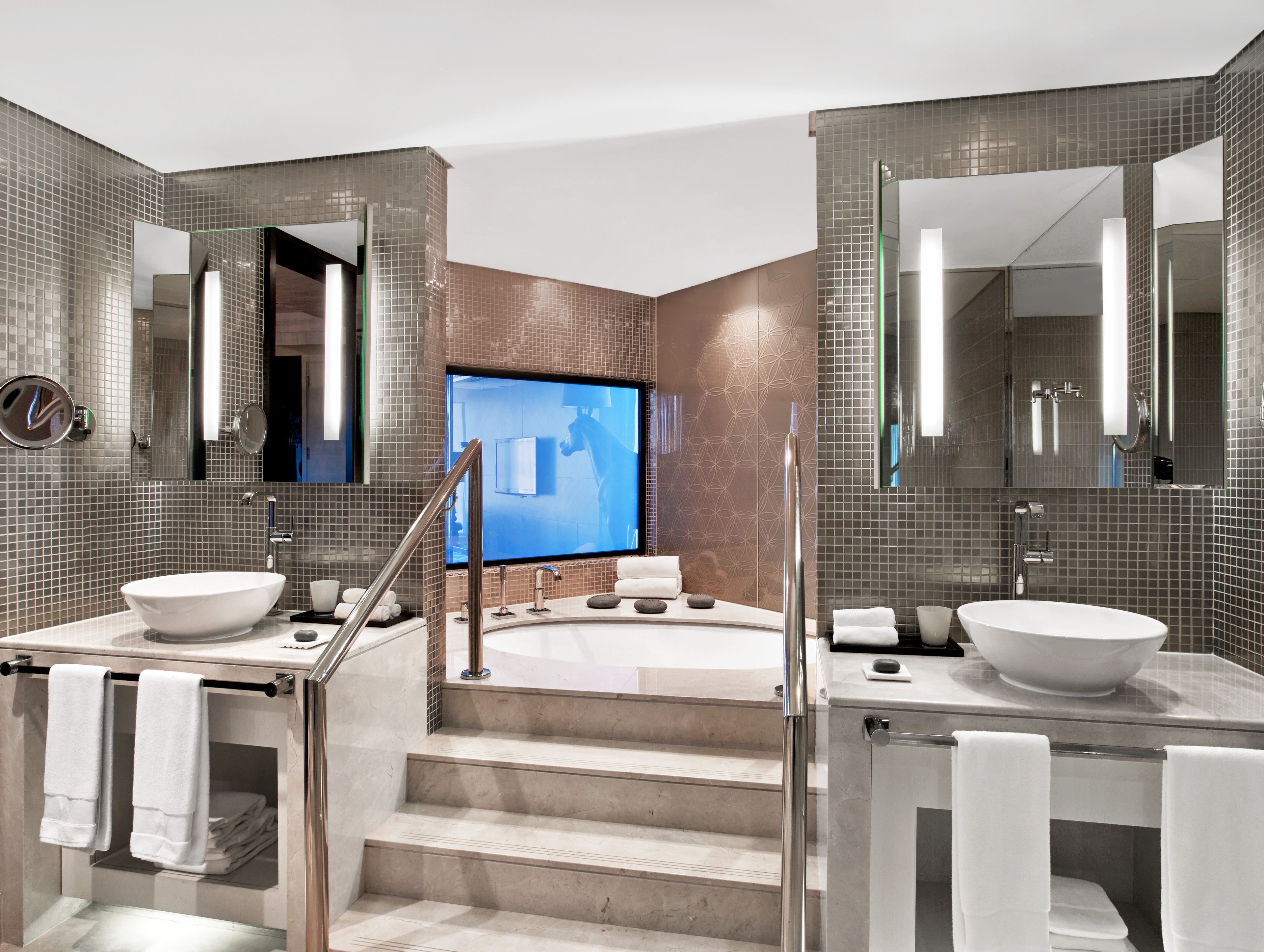 Een moderne badkamer met twee grote wastafels, een bad en een grote spiegel.