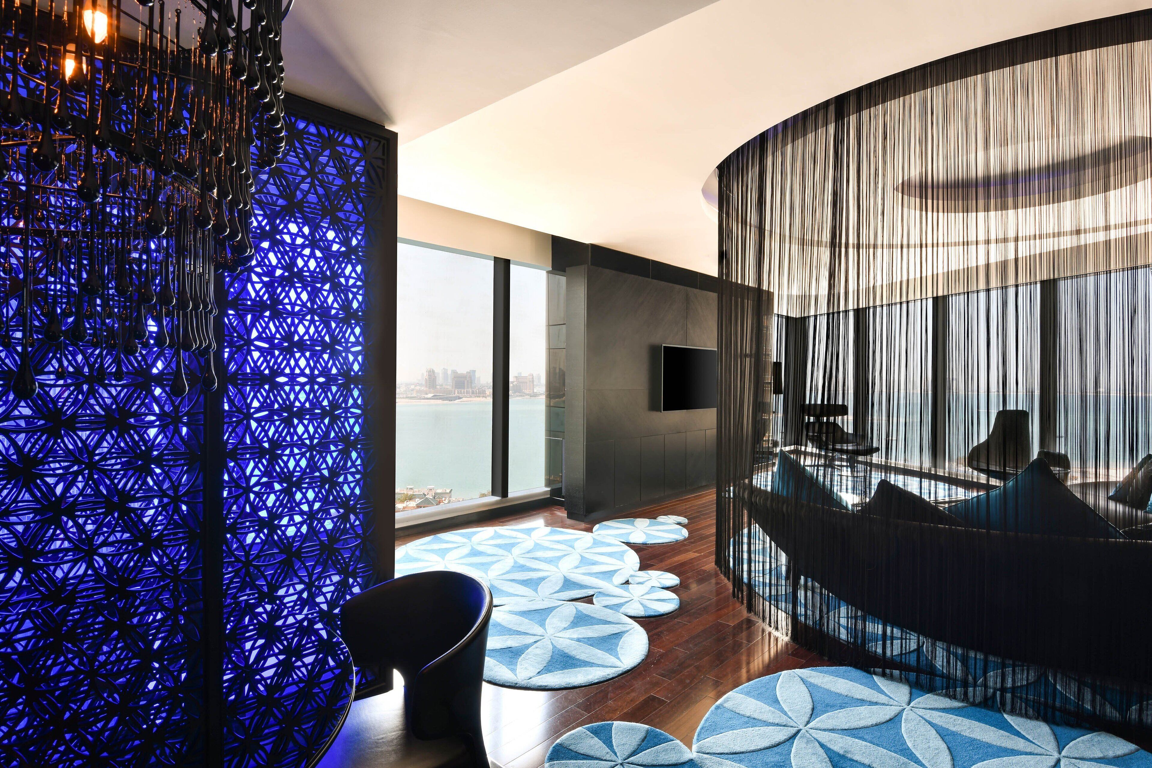 A modern interior with a curved seating area, a patterned wall, and a view of the city.