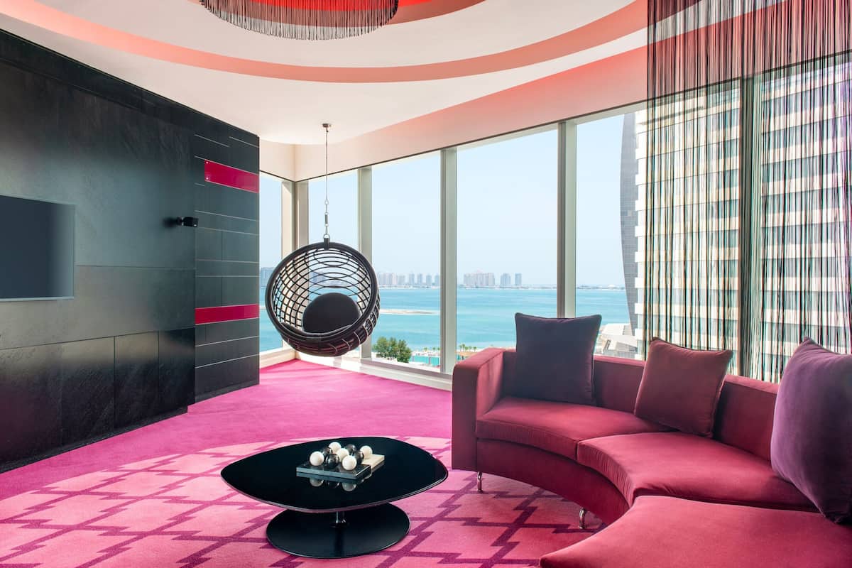 A modern living room with a curved sofa, a hanging chair, and a coffee table.