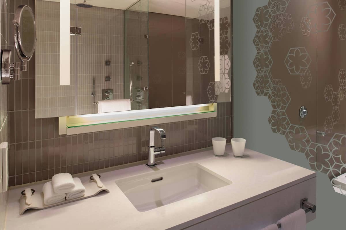 Une salle de bain moderne avec un grand miroir, un lavabo et une douche à parois de verre.
