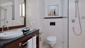 A modern bathroom with a sink, mirror, toilet, and shower.