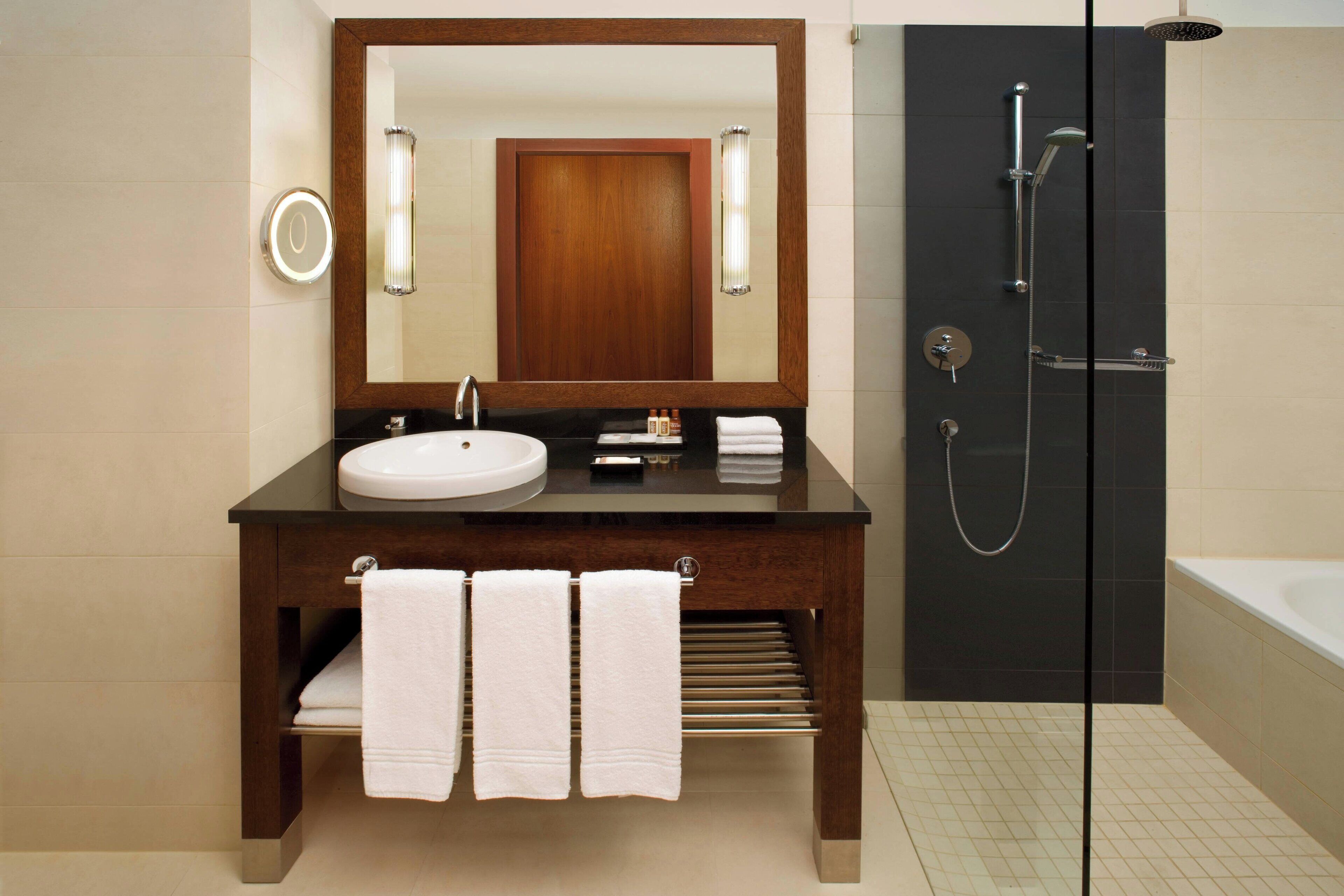 A modern bathroom with a large mirror, a sink, and a shower.