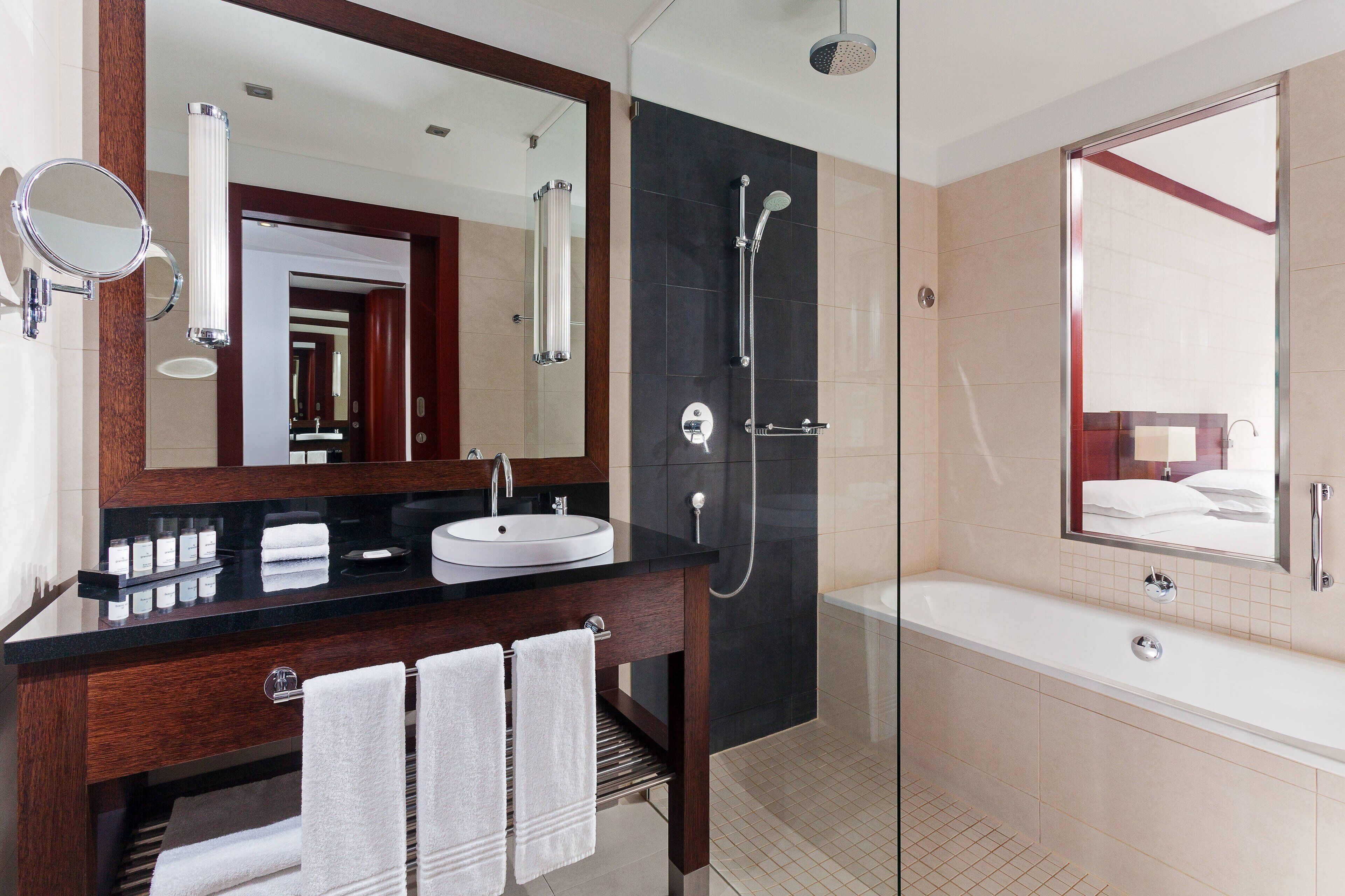 Une salle de bain moderne avec un grand miroir, un lavabo, une douche et une baignoire.