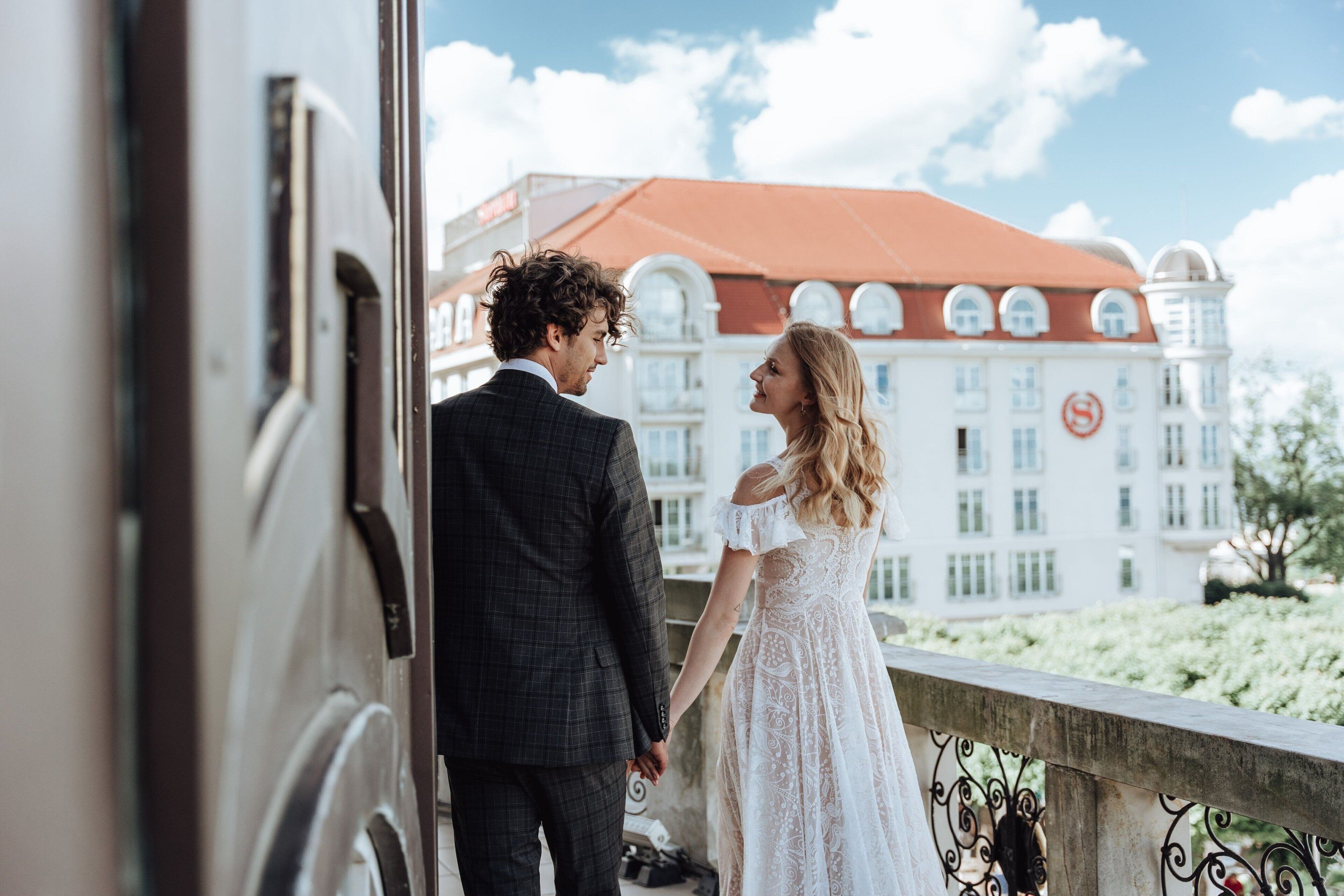 Una pareja parada en un balcón con un edificio al fondo.