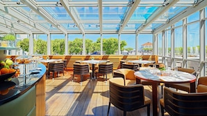 Un comedor interior con techos de vidrio, piso de madera y varias mesas y sillas.