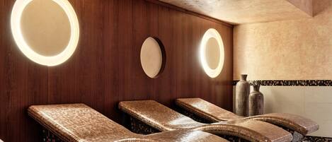 Un espacio de spa con sillones cubiertos de mosaicos, paredes de madera y espejos circulares.