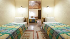 Una habitación con dos camas, techo de madera y vistas a otra habitación con una cama y una mesa.