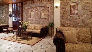 Una sala de estar con paredes de piedra, muebles de madera y piso de baldosas.
