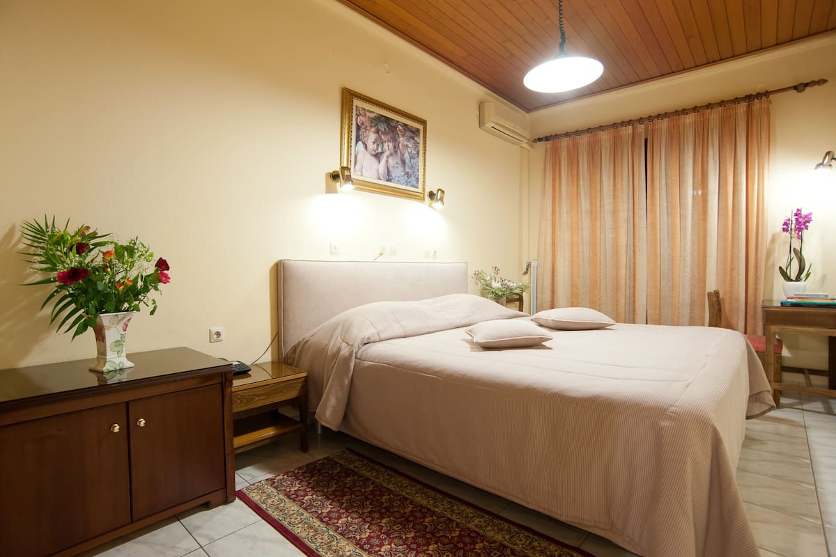Une chambre à coucher bien rangée, avec un lit, une table de chevet et une petite table d’appoint.