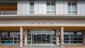 A hotel entrance with a modern design, featuring a glass facade, a set of five stars above the entrance, and a clear view of the interior through the glass doors. - Hotel Eurostars Rey Fernando (Zaragoza)