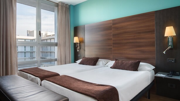 A hotel room with a large bed, two bedside tables, a desk, and a window with curtains. - Hotel Eurostars Rey Fernando (Zaragoza)