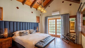 A bedroom with a large bed, wooden headboard, bedside lamps, and a bench.