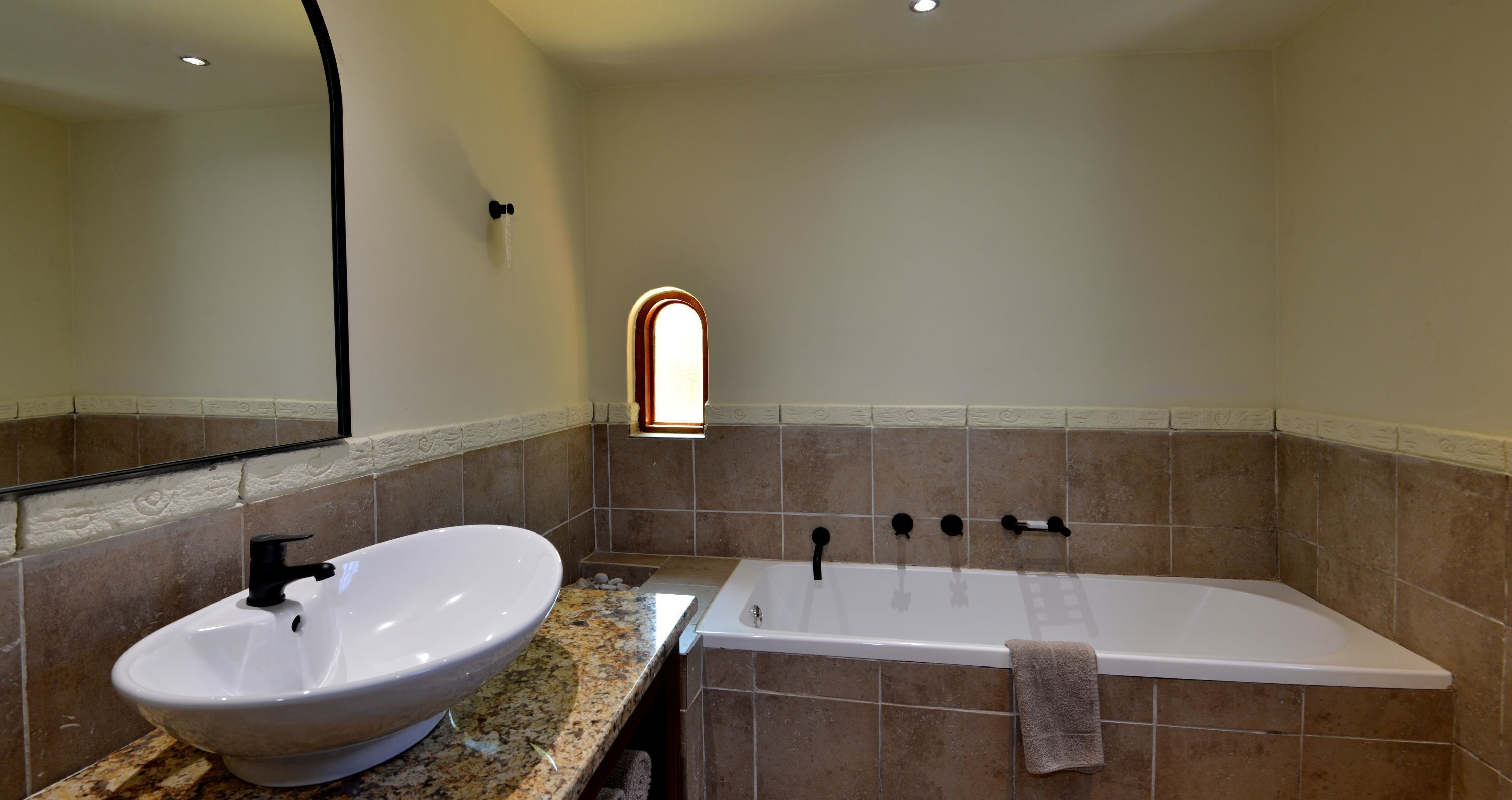 A bathroom with a white sink, a bathtub, and a mirror.