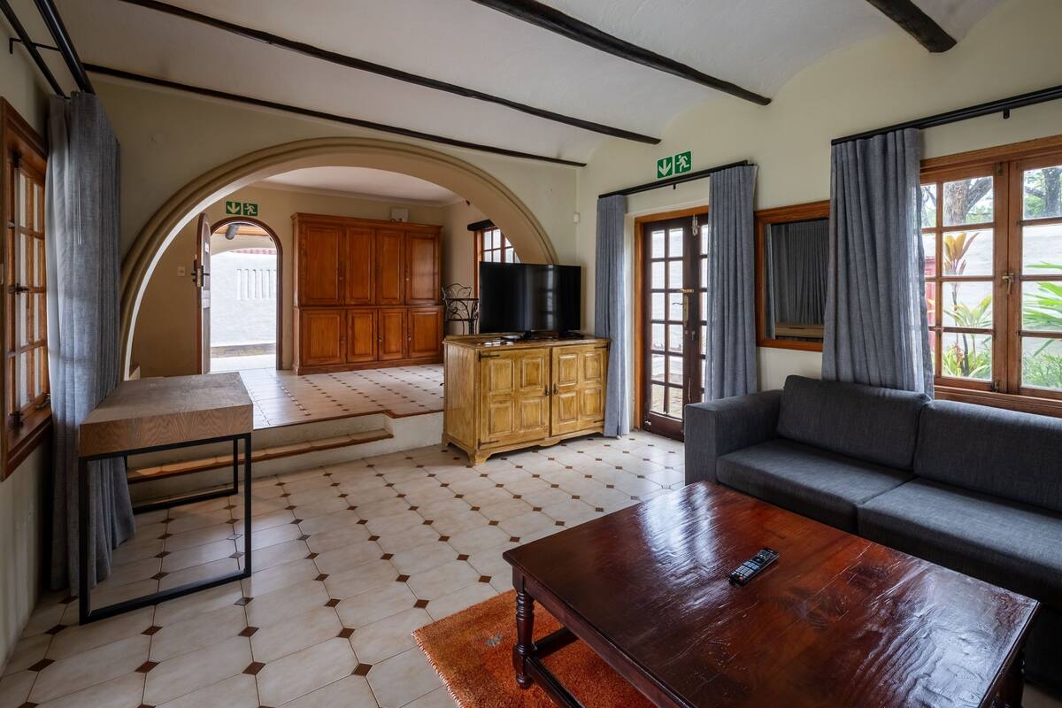 A spacious living area with a wooden cabinet, a sofa, a coffee table, and a television.