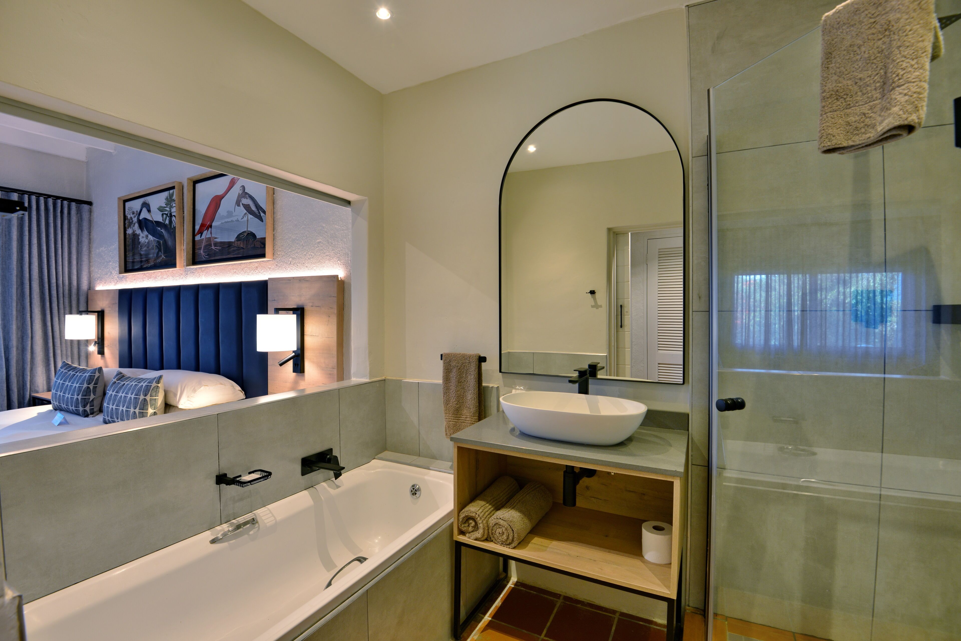 Un baño moderno con bañera, espejo grande, lavabo y zona de ducha.