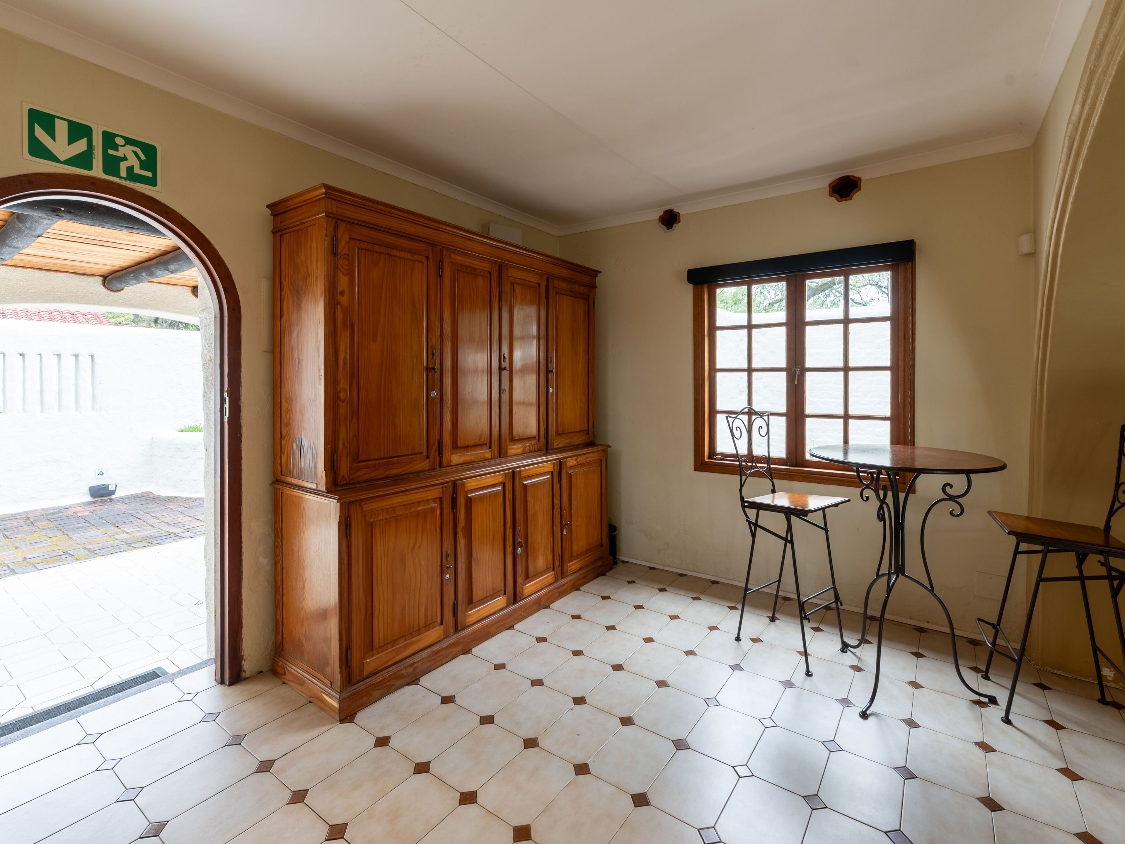 A room with a wooden cabinet, a table with two chairs, and a window with a view.