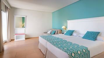 A hotel room with two beds, a sofa, a small table, and a mirror.