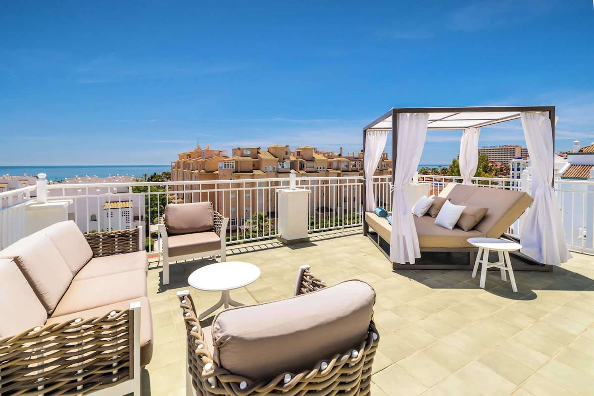 A rooftop terrace with wicker furniture, a small round table, and a canopy.