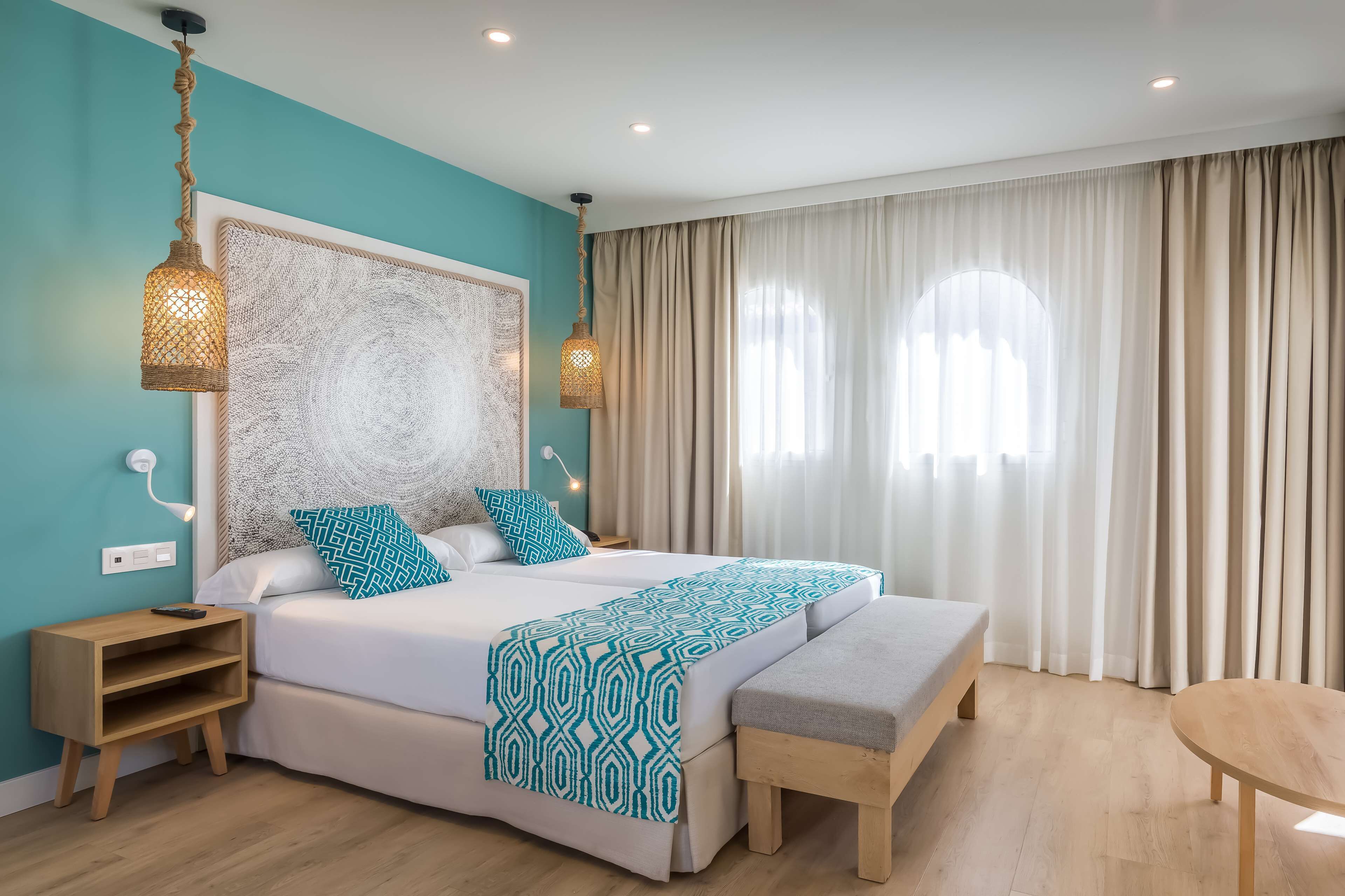 A modern bedroom with a large bed, bedside tables, a bench, and a round table.