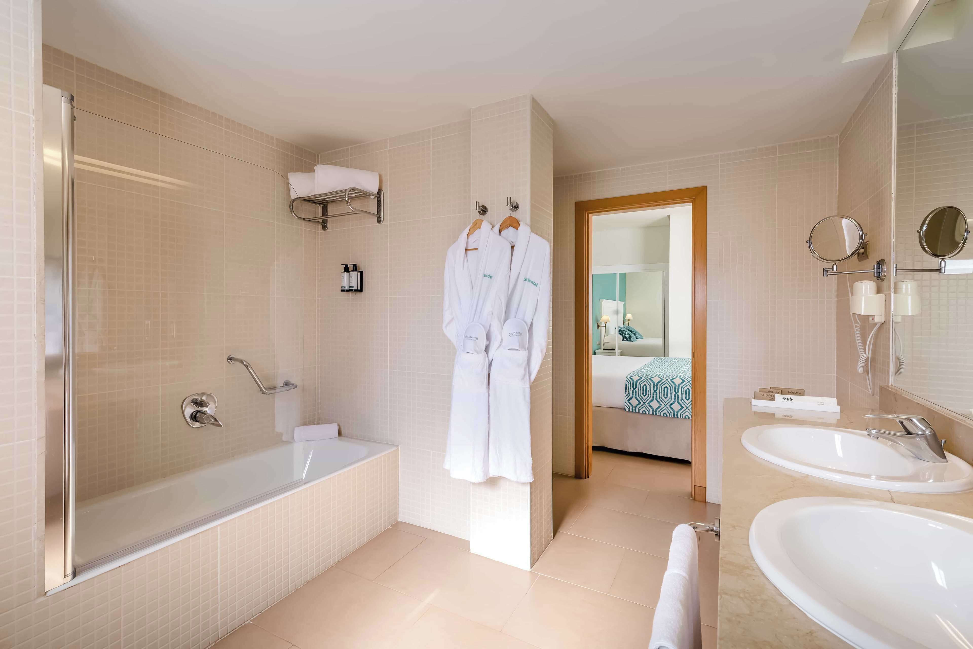 Un baño moderno con ducha de vidrio, bañera y dos lavamanos.