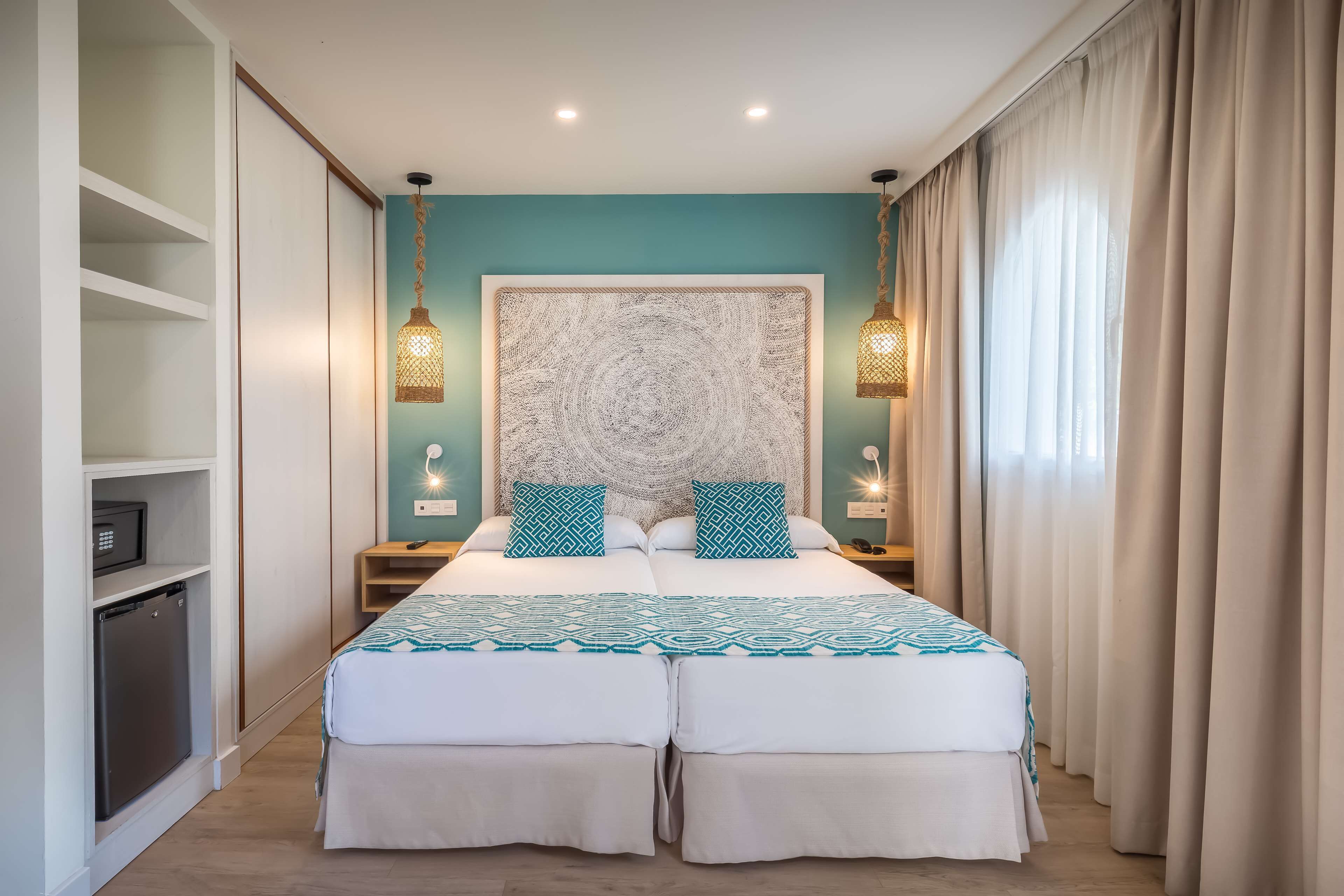 Un lit double avec une couvre-lit à motifs, deux tables de chevet avec des lampes, une grande tête de lit décorative et une armoire avec des étagères.