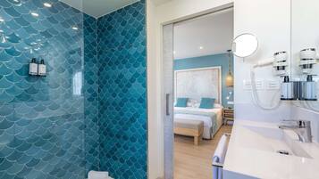 Un baño moderno con pared de azulejos azules, un lavabo blanco y zona de ducha.
