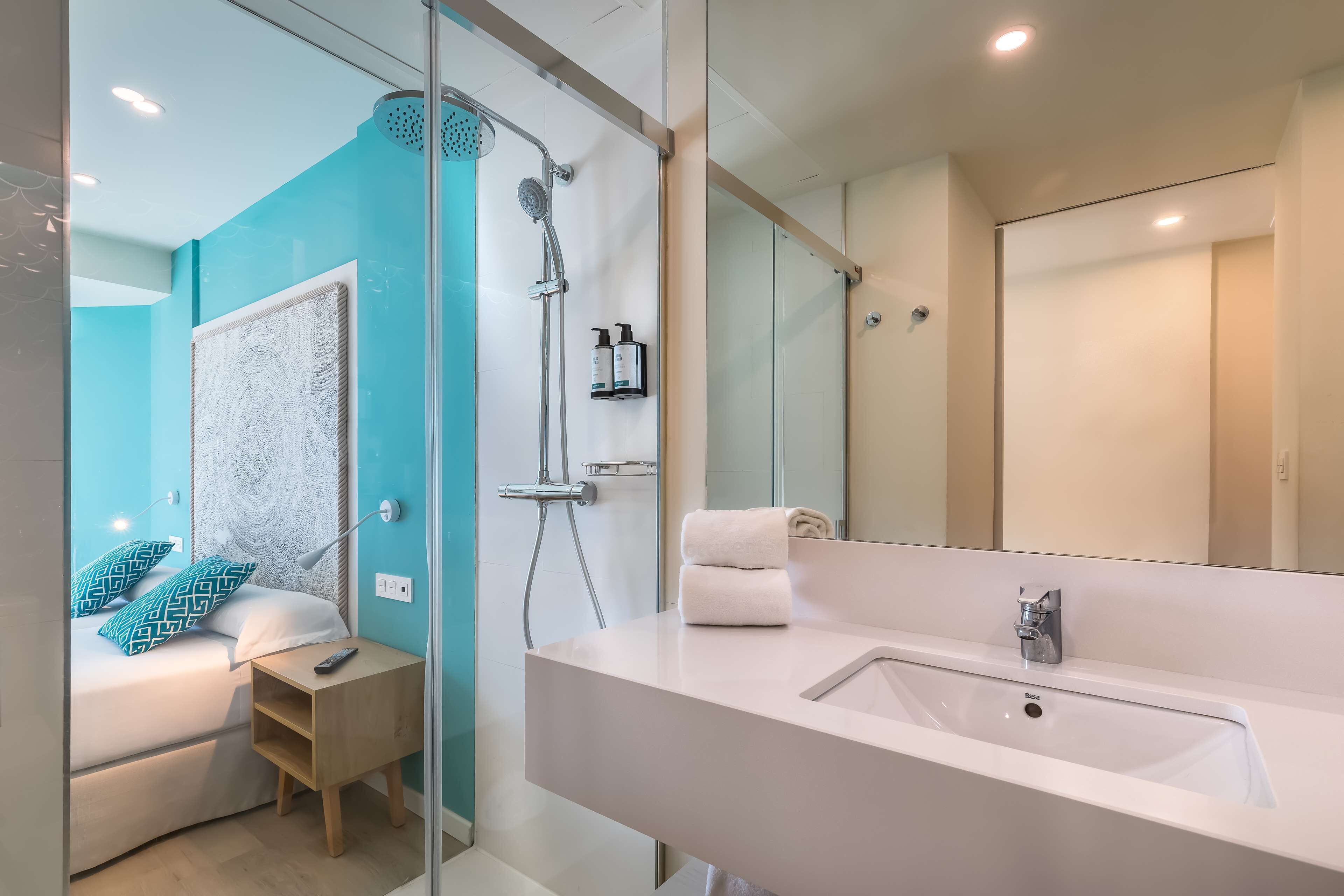 A modern bathroom with a large mirror, a white sink, and a shower.