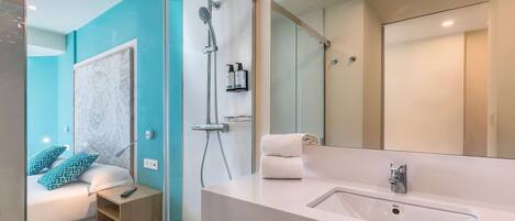 A modern bathroom with a large mirror, a white sink, and a shower.