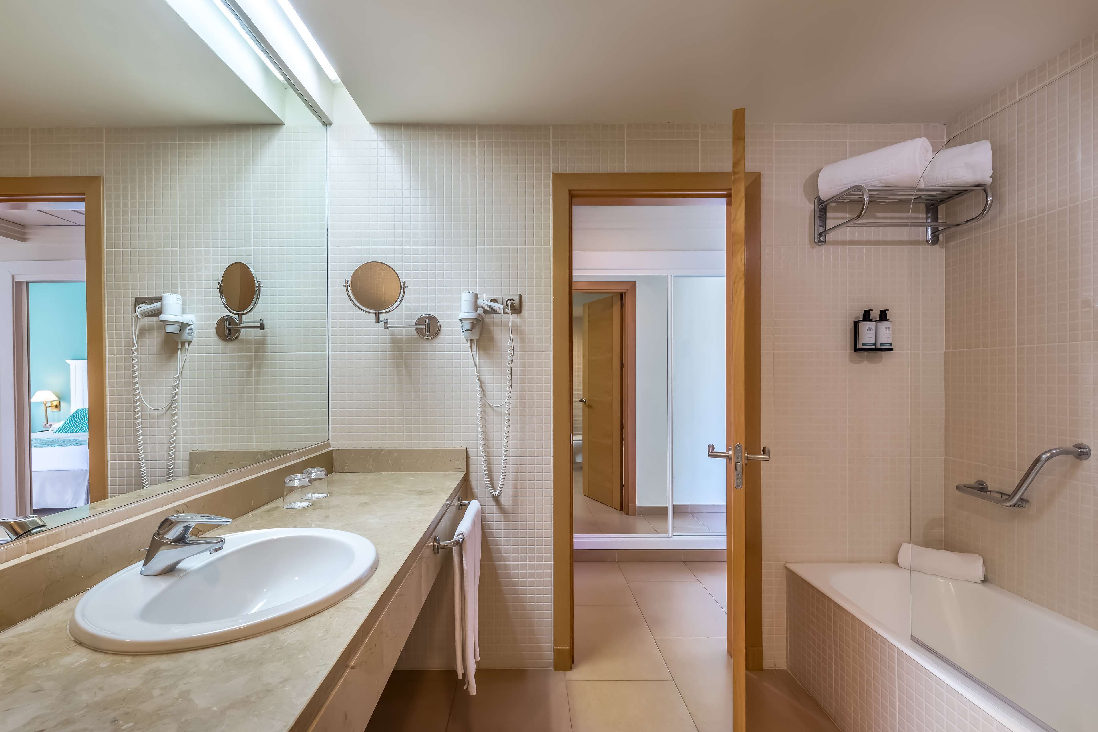 Une salle de bain moderne dotée d’un grand lavabo, d’un miroir, d’un porte-serviettes et d’un espace douche.