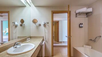 A modern bathroom with a large sink, mirror, towel rack, and shower area.
