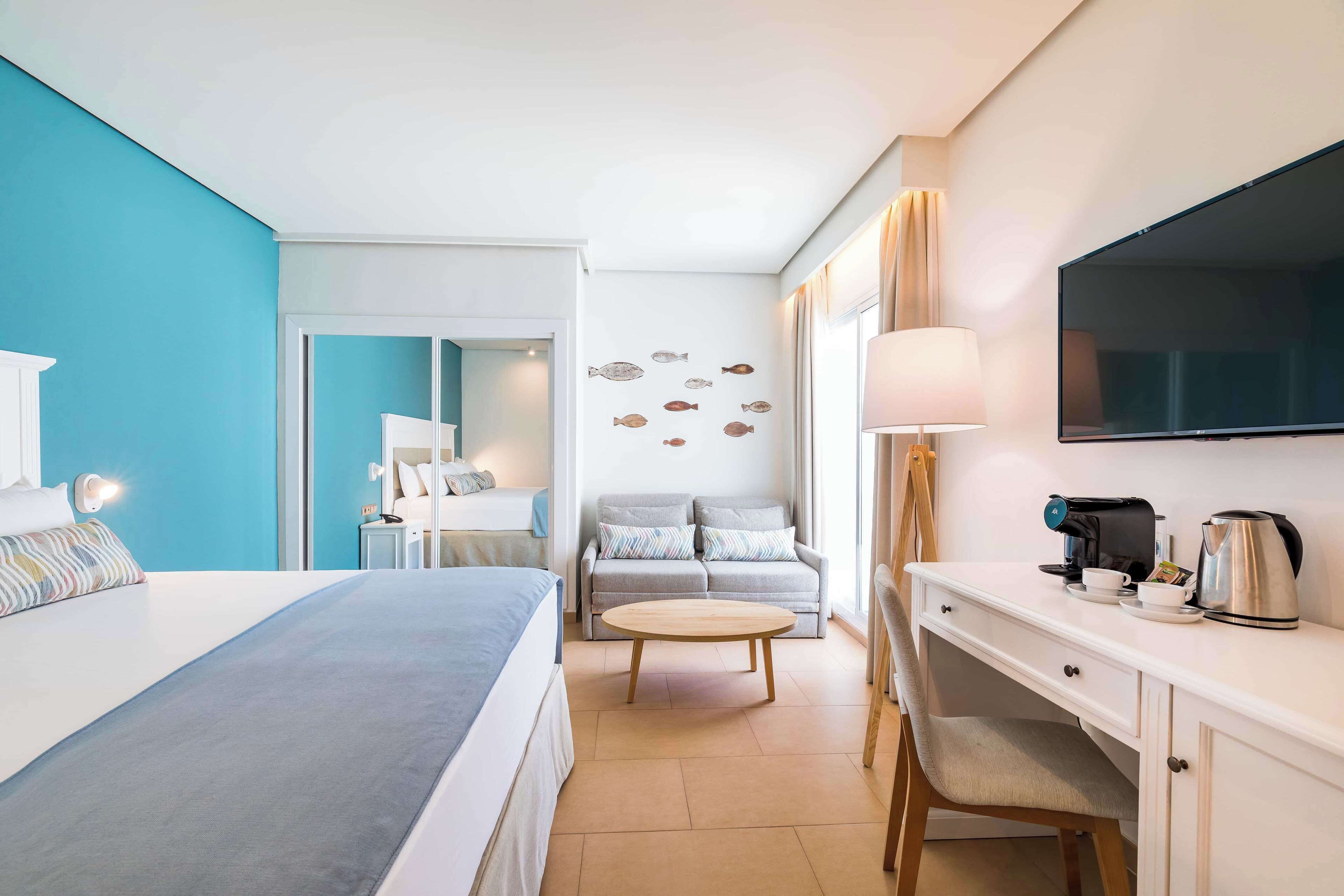 A hotel room with a bed, a desk, a coffee maker, and a TV.