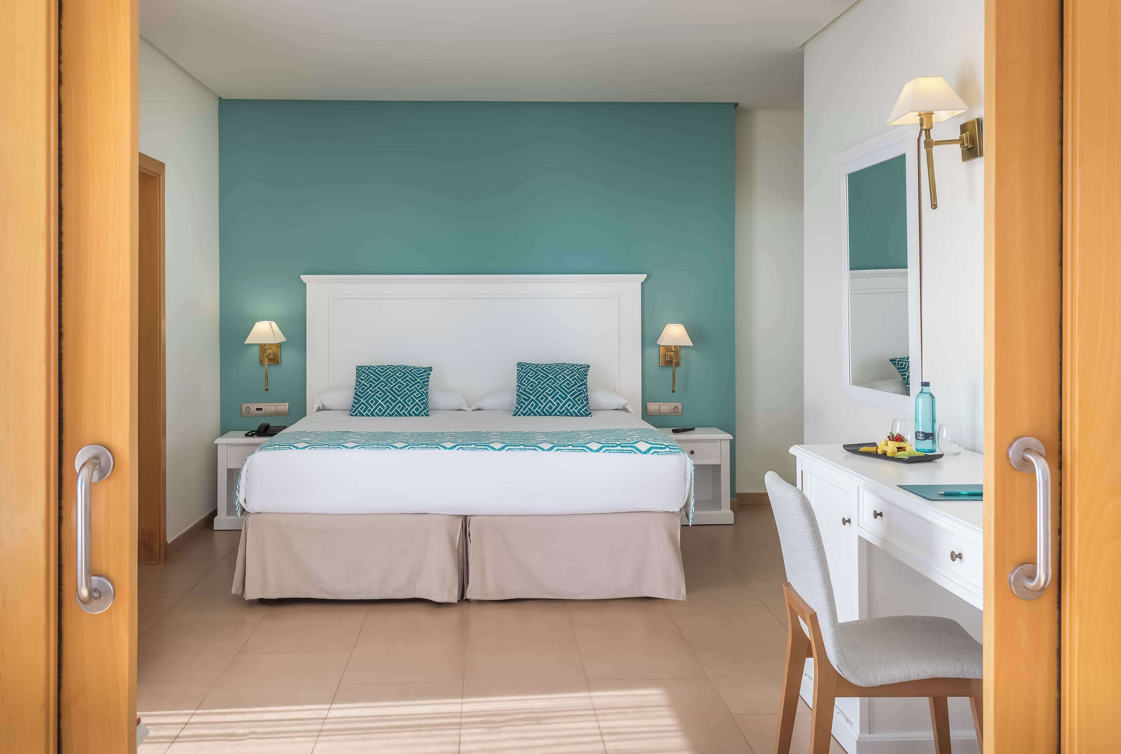 A bedroom with a bed, bedside tables, a desk, and a chair.