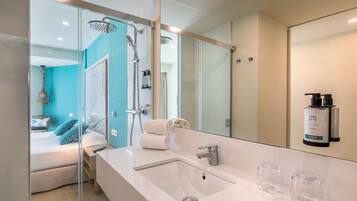 A modern bathroom with a large mirror, a white sink, and a shower area.