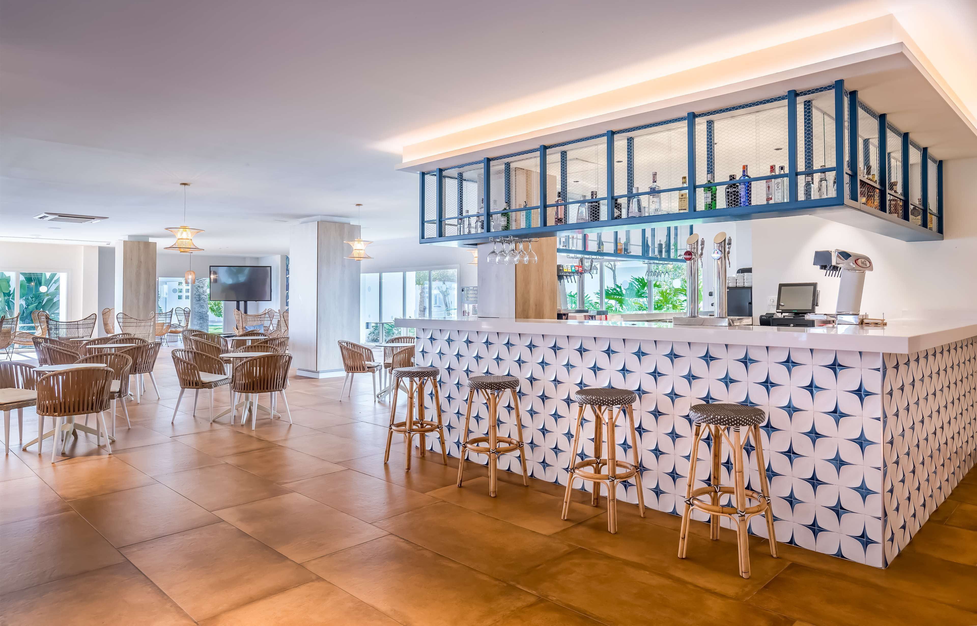 A modern bar area with a high counter, bar stools, and a variety of bottles.
