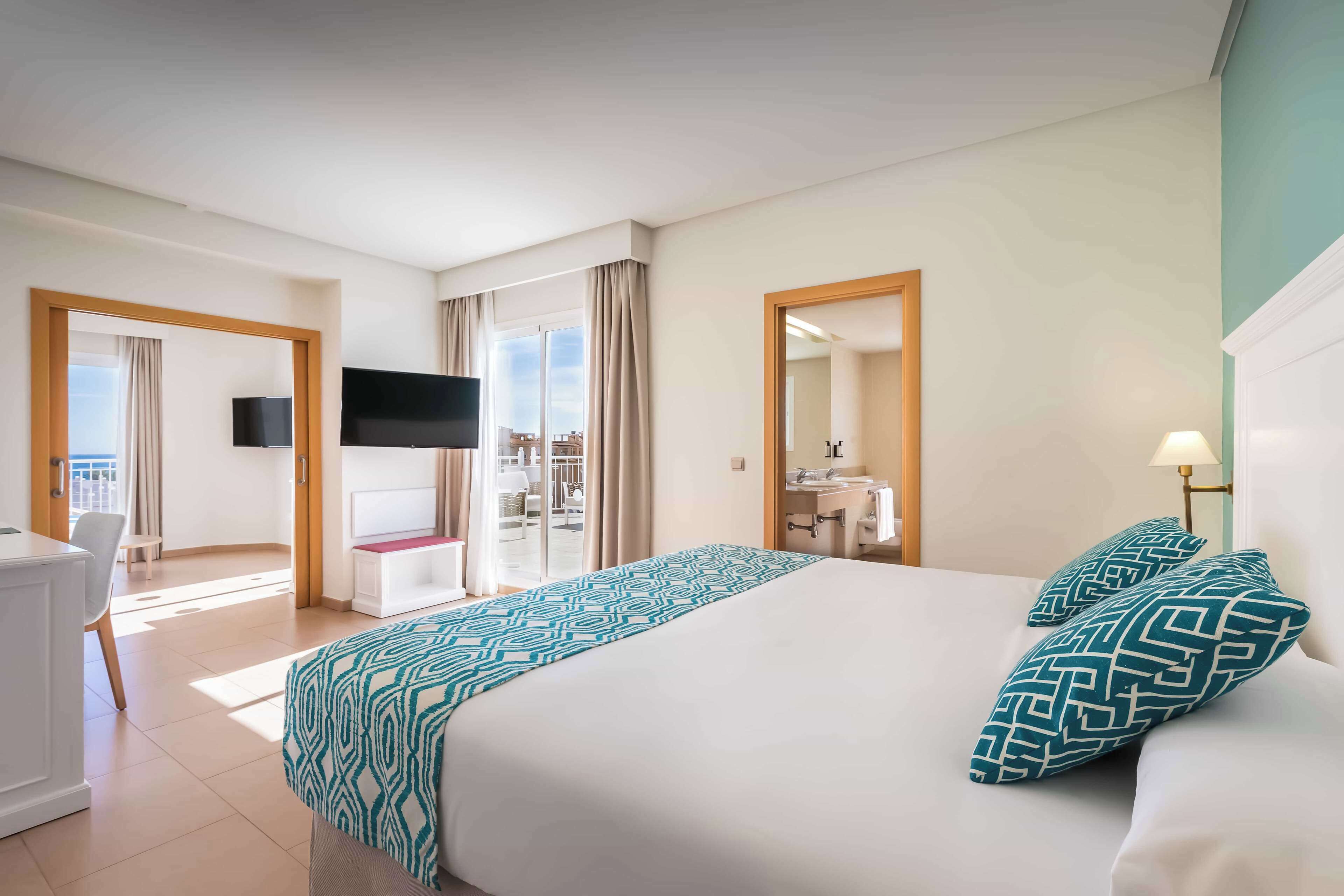 Une chambre d’hôtel avec un grand lit, une télévision, un bureau et un balcon avec vue.