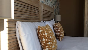 A neatly made bed with white and brown patterned pillows, a wooden headboard, and a wall with a floral wallpaper pattern. - Hotel Mona Lisa (La Baule-Escoublac)