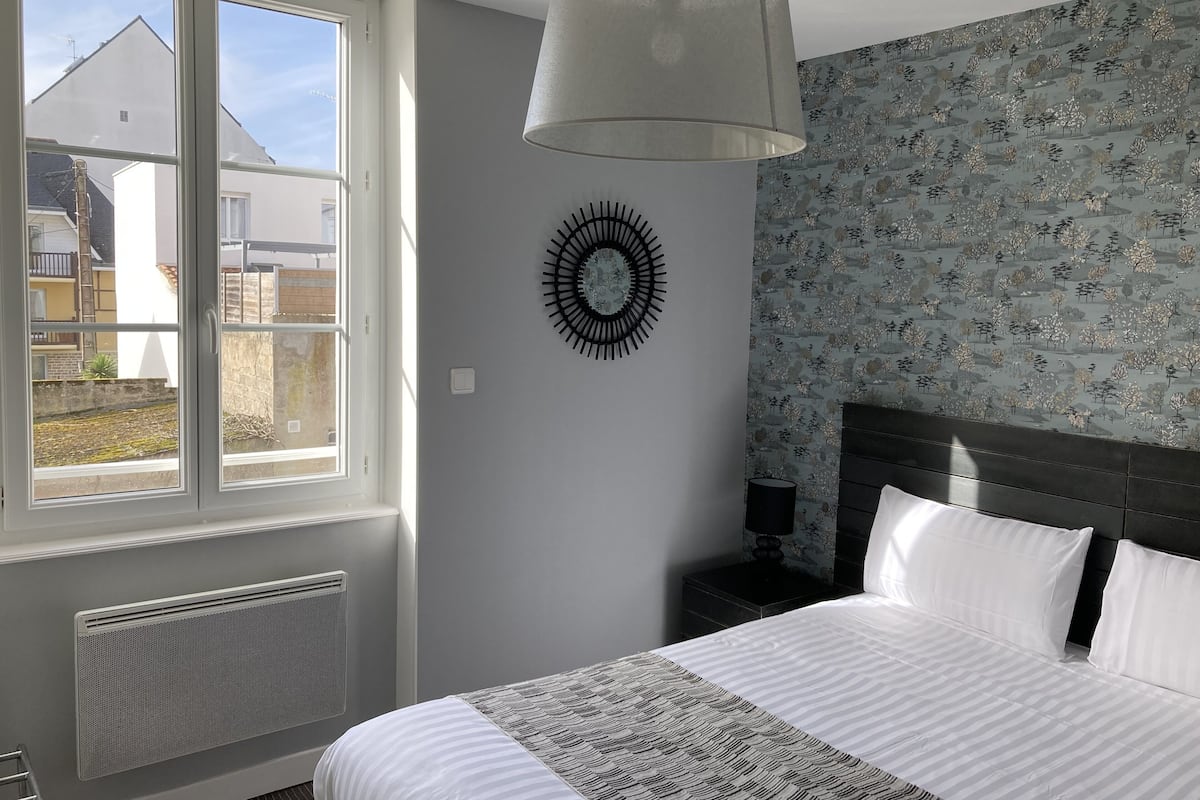 Un dormitorio con cama, ventana, reloj de pared y radiador.