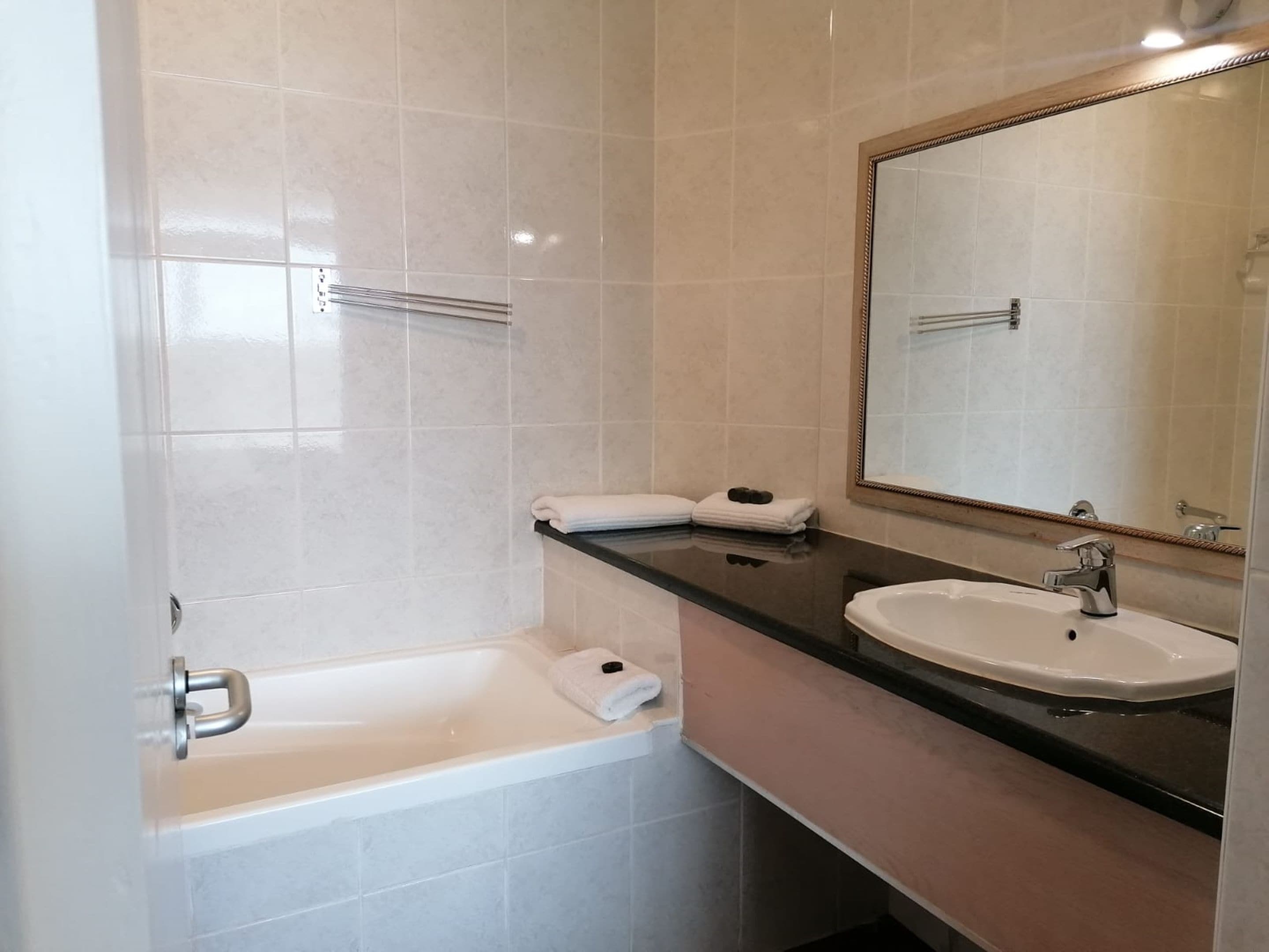 A modern bathroom with a bathtub, a sink, and a large mirror.